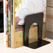 A black heavy-gauge steel Universal bookend on a table holding a book.