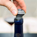 A person using a Vacu Vin wine saver vacuum pump to open a bottle of wine.