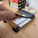 A person using an X-Acto paper cutter to cut a stack of colorful paper.