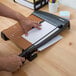 A person using an X-Acto heavy-duty paper cutter to cut paper.