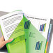 A hand holding a green and white book with graphs and charts using Avery Multi-Color Plastic Insertable Tab Dividers.