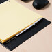 A file folder with a yellow tab and yellow paper in a black desk.
