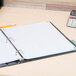 A Universal white 5-tab divider set on a white binder with papers and a calculator.