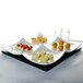 A CAC white porcelain divided tasting plate with appetizers and desserts on it.