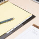 A Universal 5-tab divider set inserted into a clipboard with a pen and paper on it.
