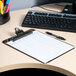 A Universal smoke plastic clipboard with a black rim on a table with a pen and keyboard.