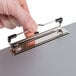 A hand holding a Universal plastic brushed aluminum landscape clipboard with a metal clip.