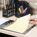 A hand inserting a Universal clear extended length divider into a yellow binder.