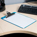 A blue Universal plastic clipboard with a paper on a desk.