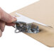 A hand holding a Universal brown hardboard clipboard with a metal clip.