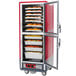 A red commercial holding cabinet with trays of food inside.