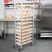 A Winholt stainless steel platter cart holding trays of food.