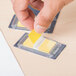 A person using a Universal yellow sticky page flag dispenser to mark a page with a yellow sticky page flag.