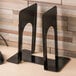 A black steel Universal economy standard bookend on a wood surface.