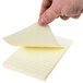 A hand holding a yellow lined paper with a Universal yellow sticky note on it.