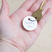 A hand holding a key with a metal rimmed white card stock key tag with a key ring.