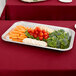 A Vollrath stainless steel fluted rectangular tray of broccoli, baby carrots, and tomatoes on a table.