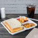 A Huhtamaki Chinet white molded fiber cafeteria tray holding a sandwich, cheese, and fruit.