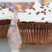 A white fluted Hoffmaster mini baking cup with a chocolate cupcake inside.