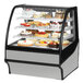 A True refrigerated bakery display case with cakes on it.