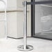 A Lancaster Table & Seating stainless steel crowd control stanchion with a black retractable belt.