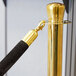 A gold pole with black rope ends on a Lancaster Table & Seating stanchion.