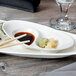A Reserve by Libbey white porcelain divided dish with food on it, including sushi, and chopsticks and sauce.