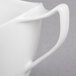 A close-up of a white Royal Rideau porcelain creamer with a handle.