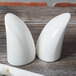 A pair of white porcelain Royal Rideau pepper shakers on a wood surface.
