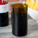 An amber Arcoroc wine tumbler filled with liquid next to a bowl of chips.