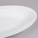 A close-up of a white Reserve by Libbey Royal Rideau porcelain platter with a curved edge.