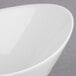 A close-up of a white oval porcelain bowl with a curved edge.