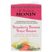 A carton of Monin Strawberry Banana Fruit Smoothie Mix with a close-up of a banana and strawberries.