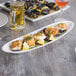 A Reserve by Libbey oval porcelain tray with food on a table.