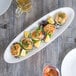 A Reserve by Libbey white porcelain tray with crab cakes and lemon wedges on a table.