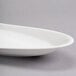 A white oval porcelain tray with a curved edge.