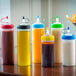 A group of Tablecraft squeeze bottles with assorted colors on a table.