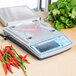 A digital scale with Edlund ClearShield cover next to red peppers and herbs.