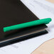 A Universal Fluorescent Green pen with a pocket clip on a black notebook.
