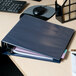 An Avery navy blue heavy-duty binder with papers and a pen on a desk.