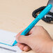 A person holding a Universal blue chisel tip highlighter over a paper.