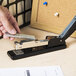 A person using a Swingline 44401S black desk stapler to staple papers.