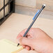 A hand using a Bic Xtra-Life mechanical pencil to write on a post-it note.