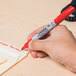 A hand writing "Sharpie" in red on a piece of paper using a Sharpie fine point red marker.