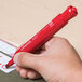 A hand holding a Universal red chisel tip desk style permanent marker over a piece of paper.