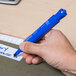 A person using a Universal blue chisel tip permanent marker to write on paper.