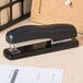A close-up of a Bostitch black stapler on a black surface.