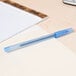 A Bic blue medium point pen on a piece of paper next to a pad of paper.