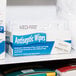 A box of Medi-First antiseptic wipes on a shelf.