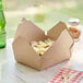 A Kraft paper take-out box with food inside on a table.